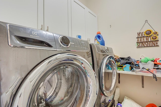 clothes washing area featuring washing machine and dryer and cabinet space