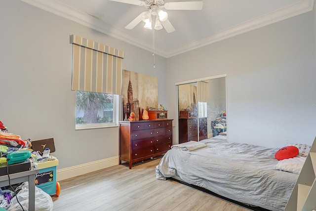 bedroom featuring a closet, baseboards, wood finished floors, and crown molding