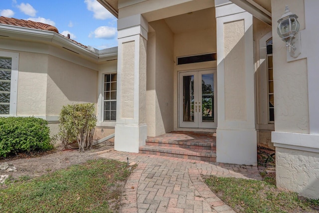 property entrance with a tiled roof, french doors, and stucco siding