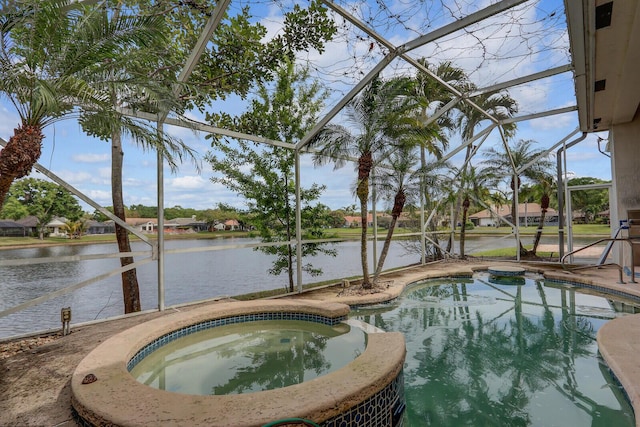 view of pool with a patio area, glass enclosure, a pool with connected hot tub, and a water view