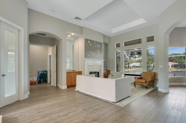 living room featuring light wood-type flooring, baseboards, visible vents, and a fireplace