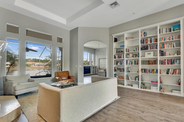 sitting room featuring wood finished floors, arched walkways, visible vents, and a tray ceiling