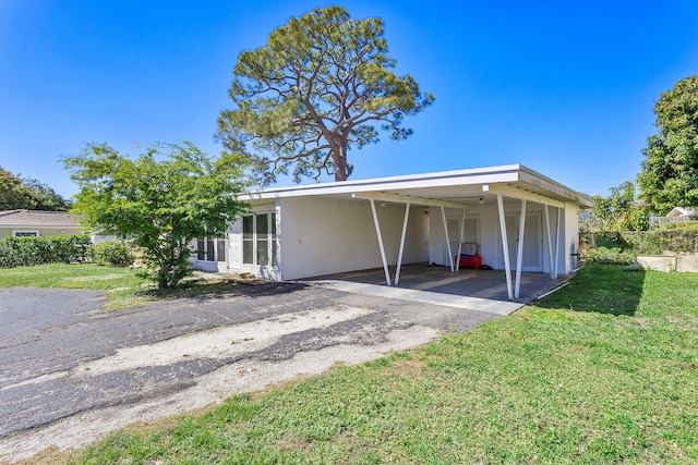 view of front of property with a carport, a front yard, driveway, and stucco siding