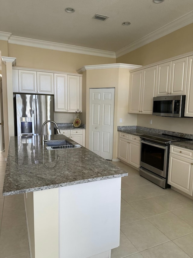 kitchen with appliances with stainless steel finishes, dark stone counters, visible vents, and ornamental molding