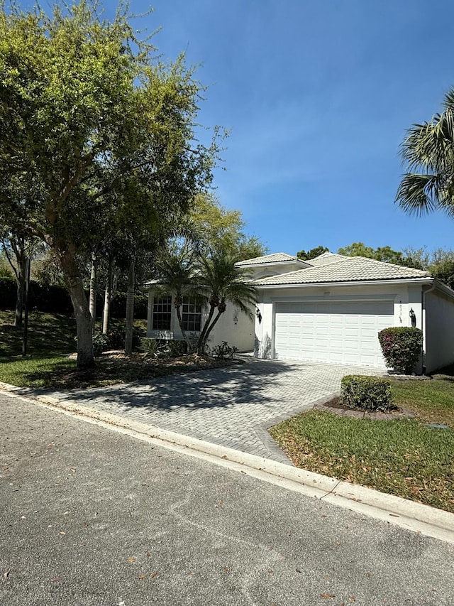 view of front of home featuring a garage, decorative driveway, a tile roof, and stucco siding