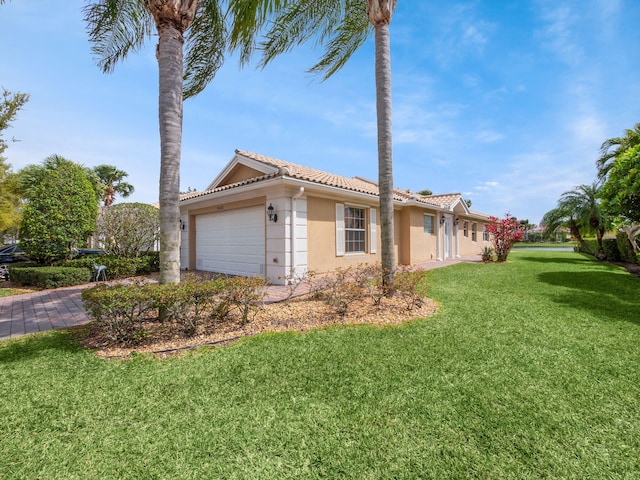 view of side of property featuring a tile roof, stucco siding, a garage, a yard, and driveway