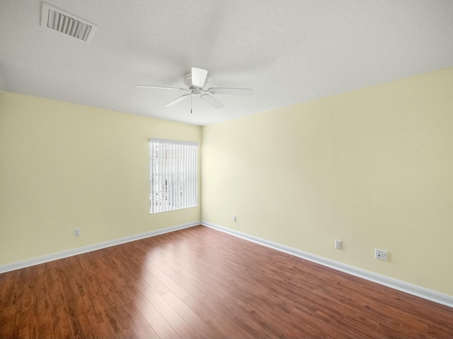 spare room with ceiling fan, wood finished floors, visible vents, and baseboards