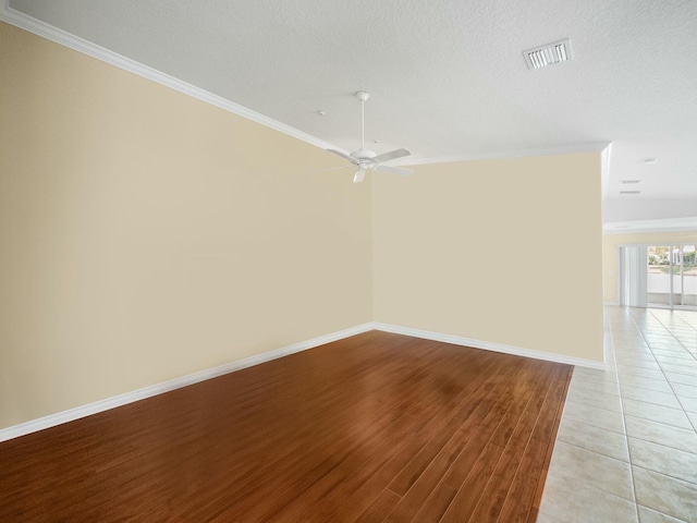 spare room featuring ornamental molding, light wood-style floors, visible vents, and baseboards