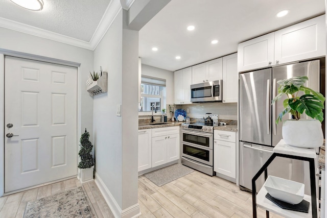 kitchen with tasteful backsplash, appliances with stainless steel finishes, white cabinets, and wood finish floors