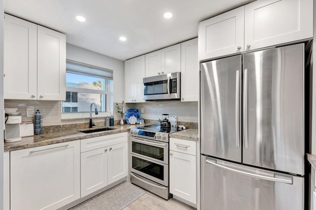 kitchen with appliances with stainless steel finishes, white cabinets, and a sink