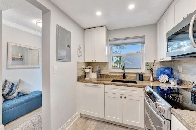 kitchen featuring electric panel, white cabinets, light wood-style flooring, stainless steel appliances, and a sink