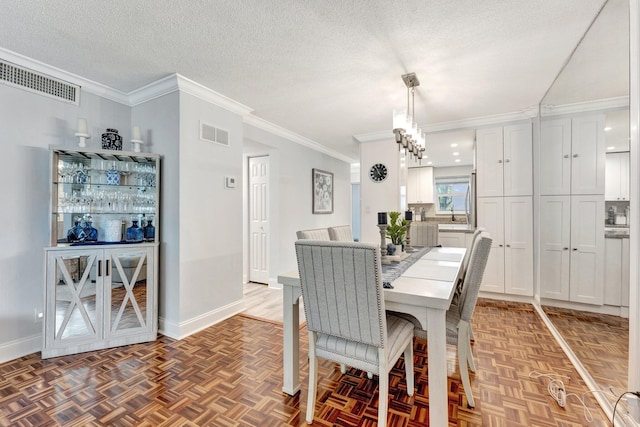 dining area with a textured ceiling, ornamental molding, visible vents, and baseboards