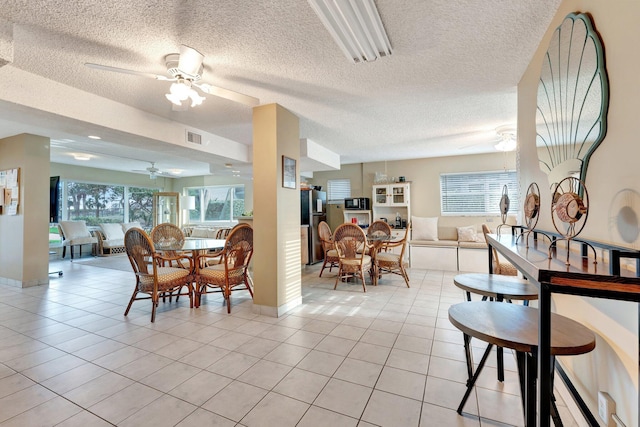 dining room with a healthy amount of sunlight, visible vents, ceiling fan, and light tile patterned floors