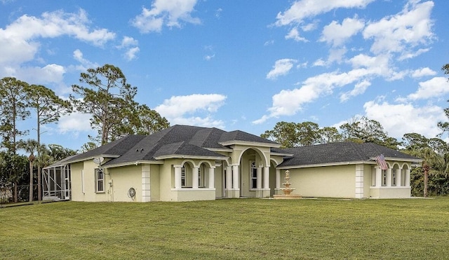 view of front of house featuring a front yard, glass enclosure, and stucco siding