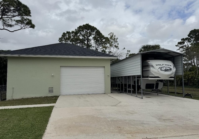 garage featuring a detached carport and concrete driveway