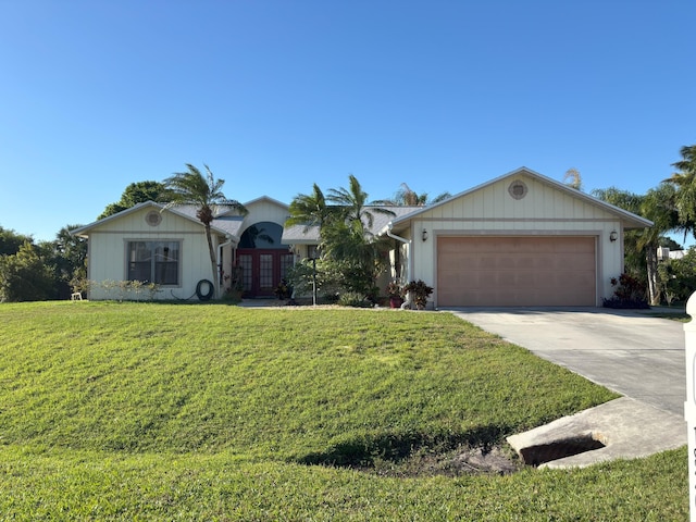 view of front facade with a garage, concrete driveway, french doors, and a front yard