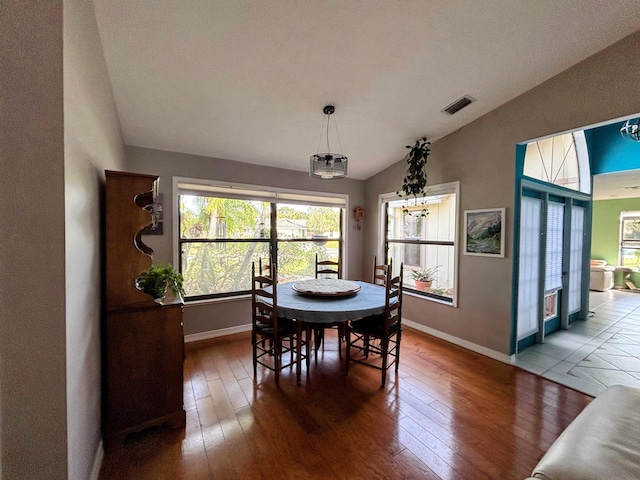 dining room with lofted ceiling, baseboards, visible vents, and hardwood / wood-style floors