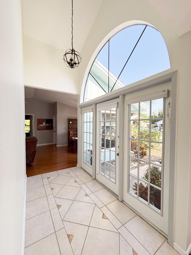 1826 SW Stratford Way, Palm City, FL 34990 - doorway featuring plenty of natural light, a chandelier, tile patterned floors, high vaulted ceiling, and baseboards