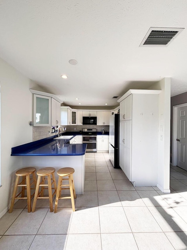 1826 SW Stratford Way, Palm City, FL 34990 - kitchen with black appliances, a peninsula, a sink, tasteful backsplash, and glass insert cabinets