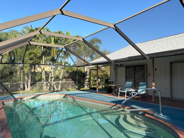 outdoor pool featuring glass enclosure and a patio