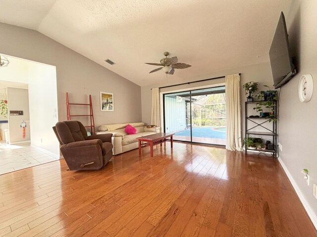 1826 SW Stratford Way, Palm City, FL 34990 - living room with vaulted ceiling, light wood-type flooring, ceiling fan, baseboards, and a textured ceiling