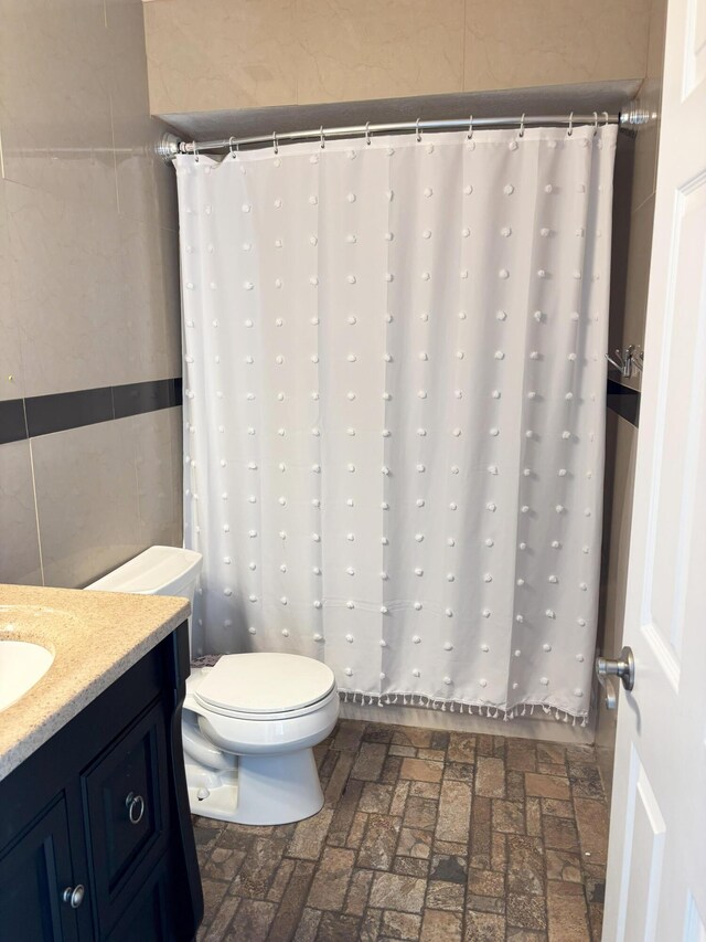 1826 SW Stratford Way, Palm City, FL 34990 - bathroom featuring brick flooring, toilet, vanity, tile walls, and a shower with shower curtain