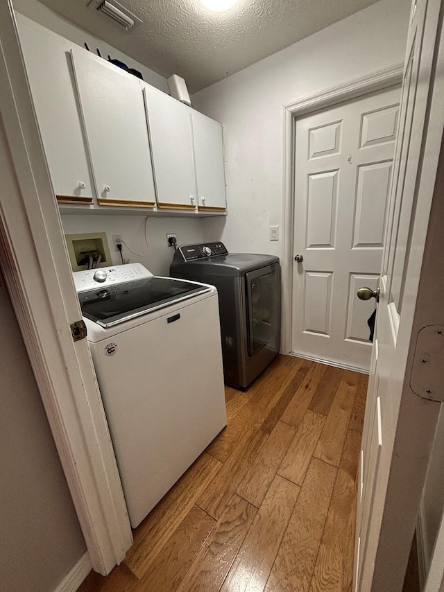 1826 SW Stratford Way, Palm City, FL 34990 - laundry area with light wood-type flooring, cabinet space, washer and dryer, and a textured ceiling