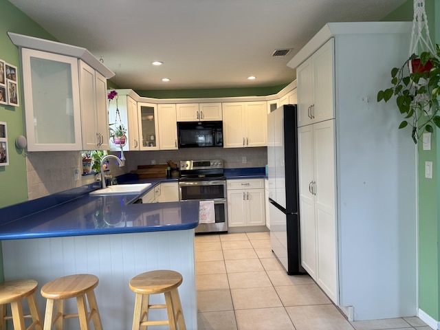 kitchen with light tile patterned floors, freestanding refrigerator, a sink, black microwave, and double oven range