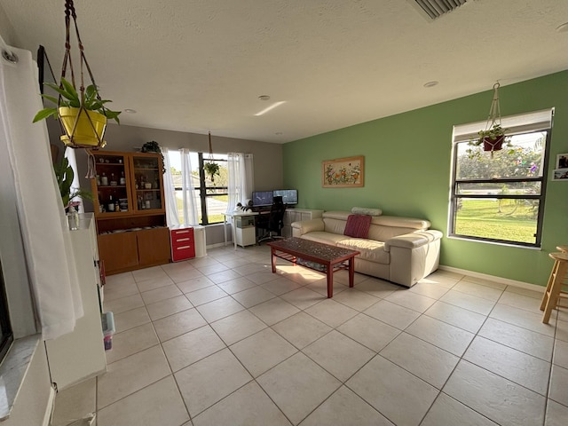 living room with baseboards, visible vents, a textured ceiling, and light tile patterned flooring