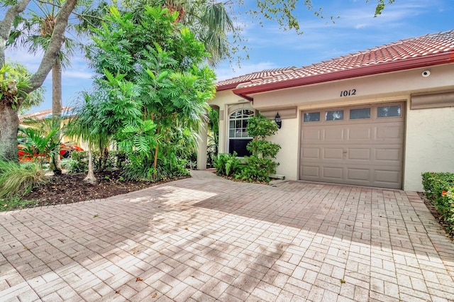 view of front of property featuring a tile roof, decorative driveway, a garage, and stucco siding