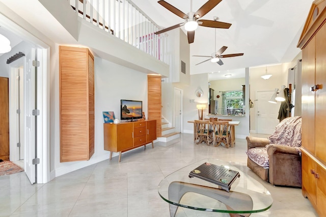 living room with stairway, baseboards, visible vents, and a towering ceiling