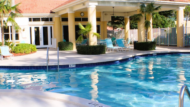 community pool featuring a patio, fence, and french doors