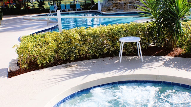 pool featuring a hot tub, a patio, and fence