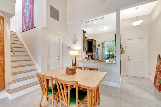 dining area featuring stairs, a high ceiling, light tile patterned floors, and visible vents