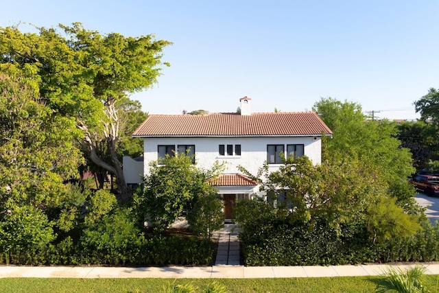 mediterranean / spanish-style home featuring stucco siding, a chimney, and a tile roof