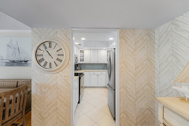 kitchen featuring light tile patterned floors, stainless steel appliances, tasteful backsplash, glass insert cabinets, and white cabinets