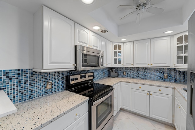 kitchen featuring light tile patterned floors, stainless steel appliances, visible vents, backsplash, and white cabinets