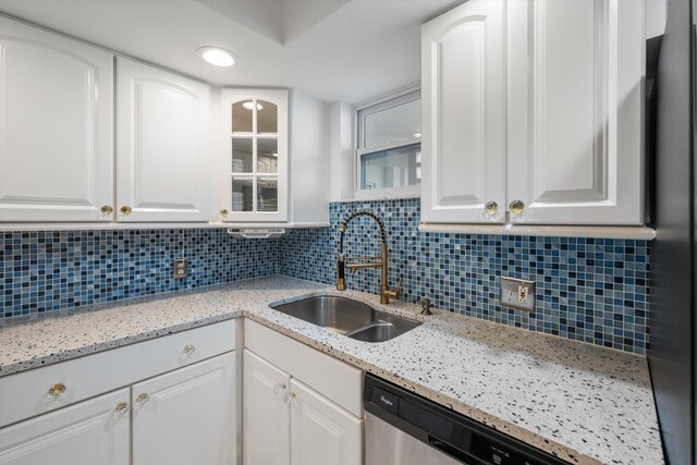 kitchen with stainless steel dishwasher, a sink, white cabinetry, and decorative backsplash