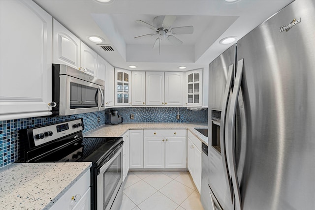 kitchen with light tile patterned floors, stainless steel appliances, visible vents, backsplash, and a raised ceiling