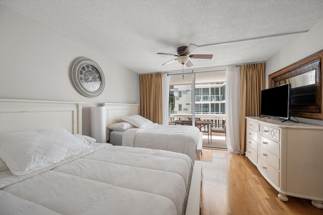 bedroom featuring light wood-style flooring, ceiling fan, access to exterior, a wall of windows, and a textured ceiling