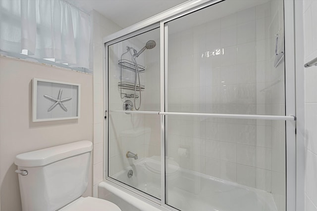 bathroom featuring combined bath / shower with glass door and toilet