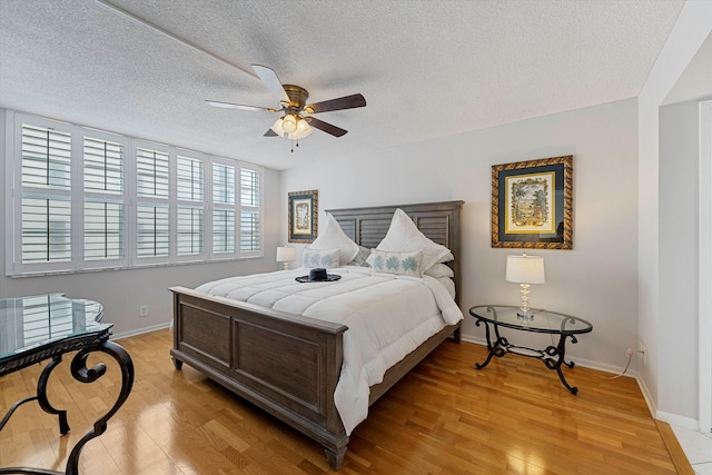 bedroom featuring light wood-type flooring, ceiling fan, a textured ceiling, and baseboards