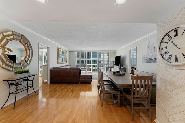 dining room featuring ornamental molding, baseboards, light wood-style flooring, and a textured ceiling