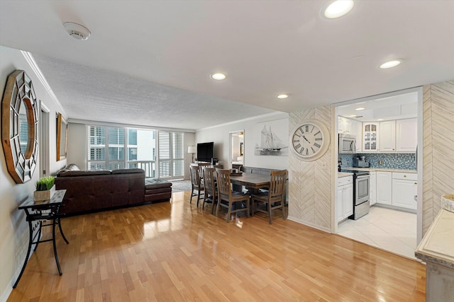 living area featuring light wood-type flooring, ornamental molding, and recessed lighting