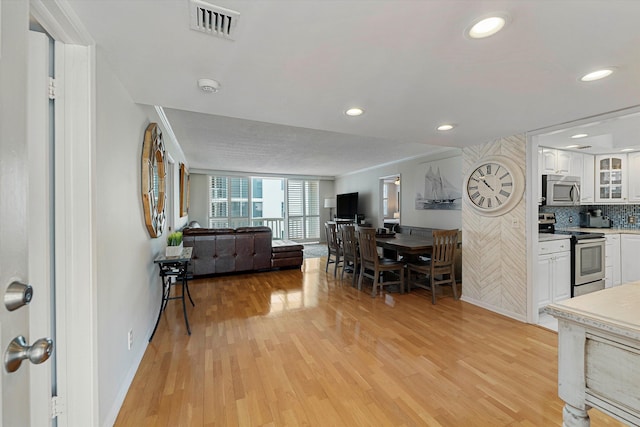 living room featuring baseboards, visible vents, ornamental molding, light wood-style floors, and recessed lighting