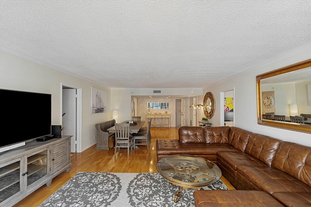 living room with a textured ceiling, ornamental molding, light wood-type flooring, and visible vents