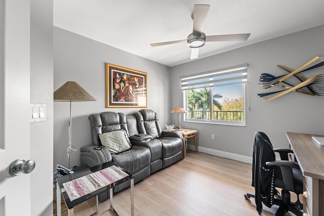 home office featuring baseboards, a textured ceiling, light wood-style flooring, and a ceiling fan