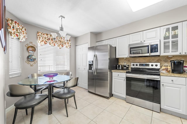 kitchen featuring a notable chandelier, white cabinetry, appliances with stainless steel finishes, tasteful backsplash, and glass insert cabinets