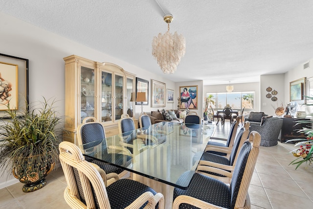 dining space featuring visible vents, a notable chandelier, a textured ceiling, and light tile patterned floors