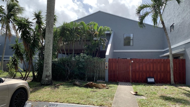 view of side of property with a lawn, fence, and stucco siding